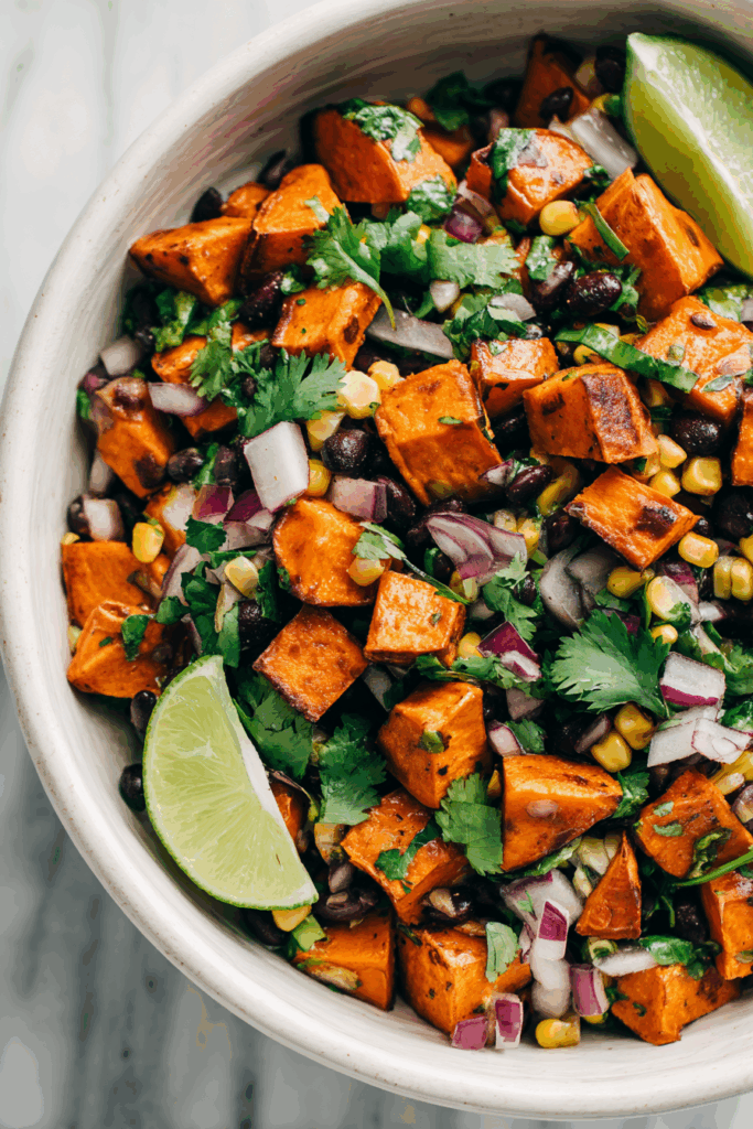 Roasted sweet potato and black bean salad with corn and lime in a white bowl.