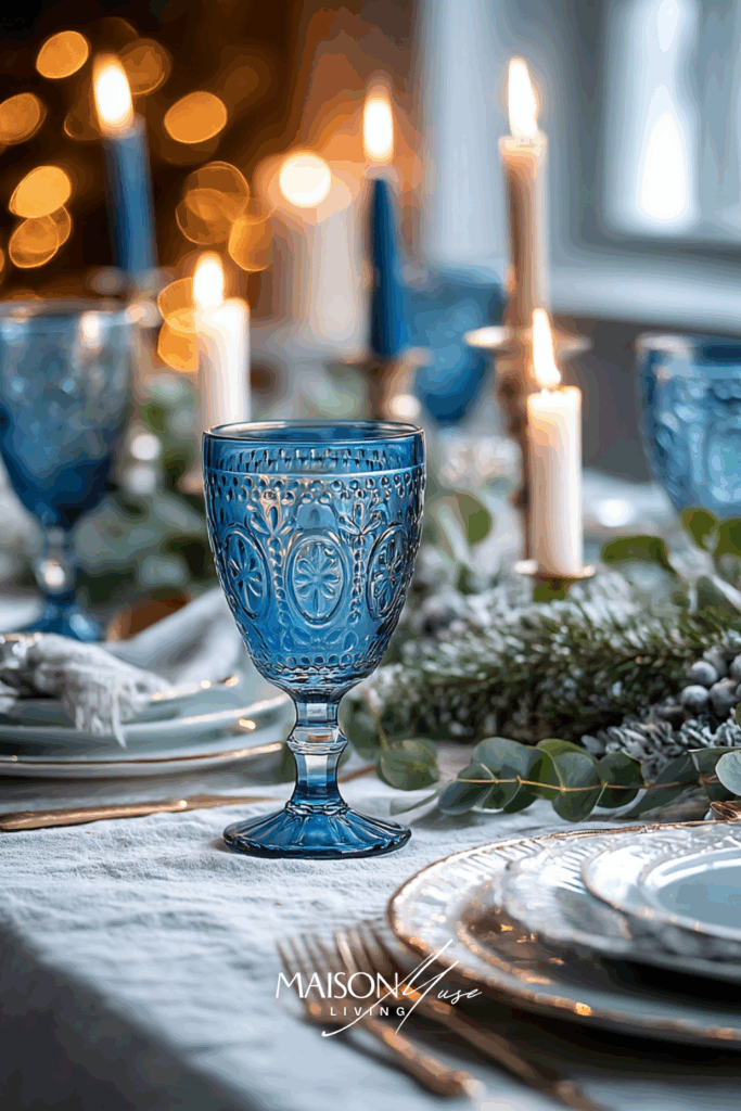 Blue glass goblets and gold flatware on a modern holiday table with bright natural daylight and white linen