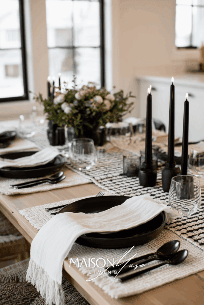 Christmas table in black and white palette, black cutlery, white linens, black taper candles