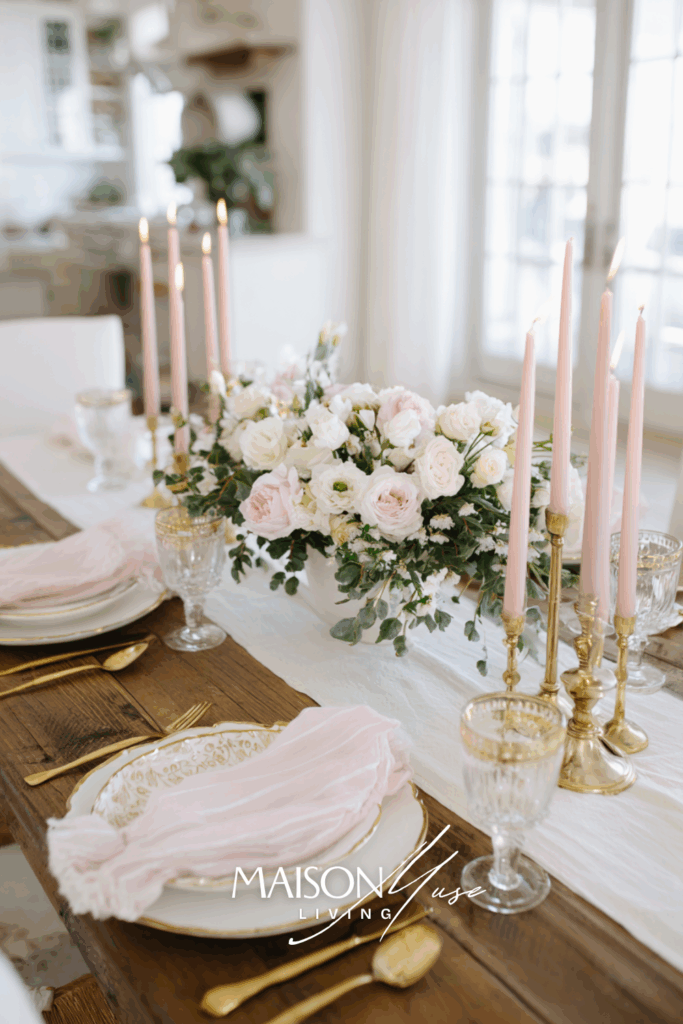 Holiday dining table styled with blush taper candles, champagne linens, golden cutlery