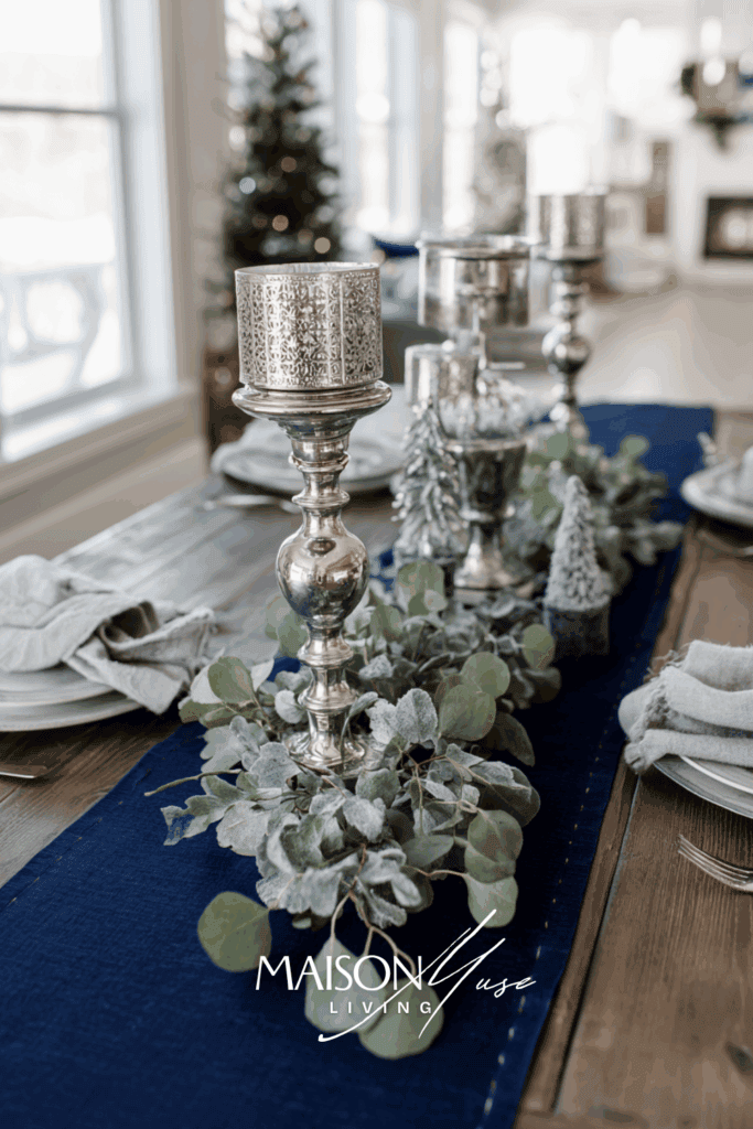 Christmas table with navy runner, silver candlesticks, frosted eucalyptus centerpiece