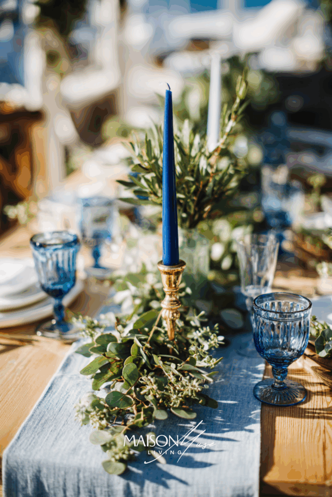 Christmas table setting with blue and olive green colored elements on the table, linen runner, eucalyptus garland and blue candles