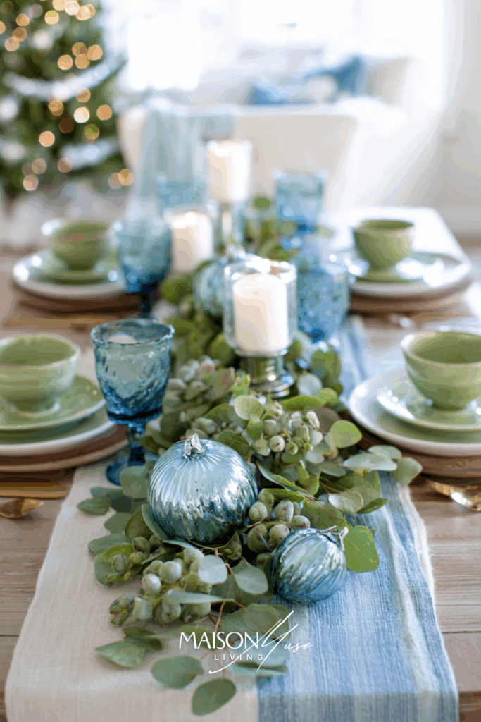 Christmas table setting with light blue and pistachio green colored elements on the table, linen runner, blue glass ornaments and white candles