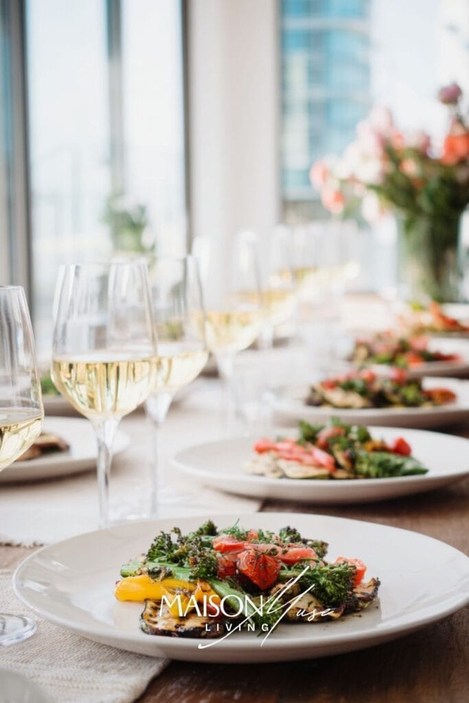 long dining table outside or in bright room, grilled vegetables, chilled wine, crisp white plates