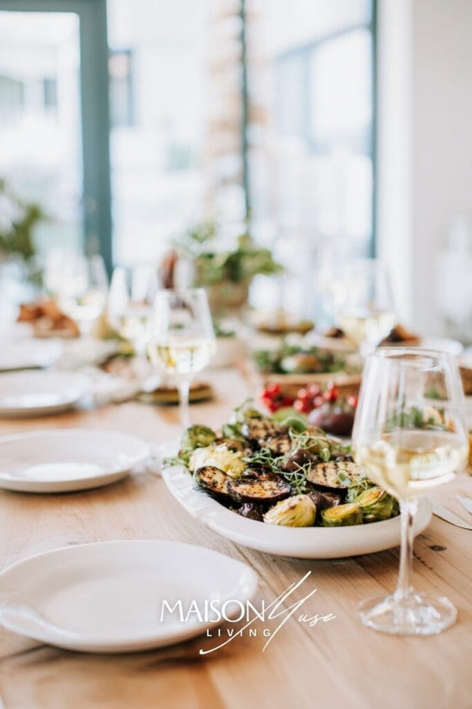 long dining table outside or in bright room, grilled vegetables, chilled wine